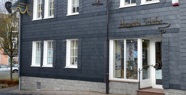 Fachwerkhaus mit Schieferfassade, Geschäftseingang der Hörgeräte Schäfer in deutscher Stadt.